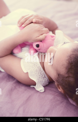 Little girl holding teddy bear while napping Stock Photo