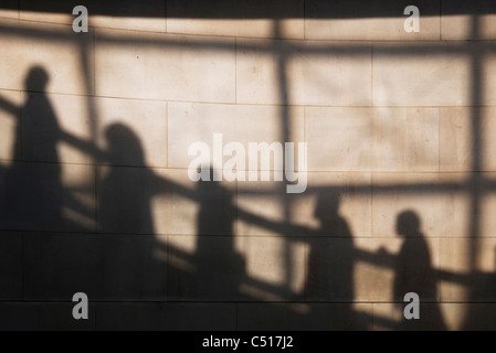 Shadow on wall of people riding escalator Stock Photo