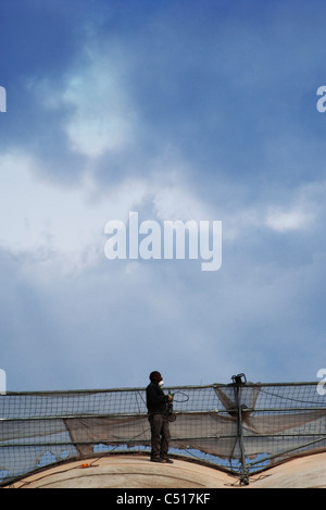 Worker standing on roof with power grinder Stock Photo