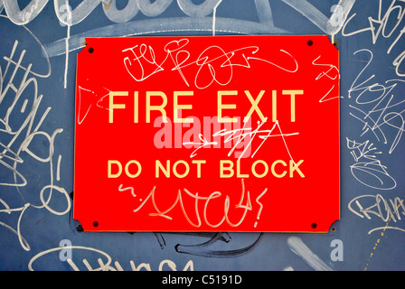 Street sign (fire exit, do not block) with graffiti on it. Stock Photo