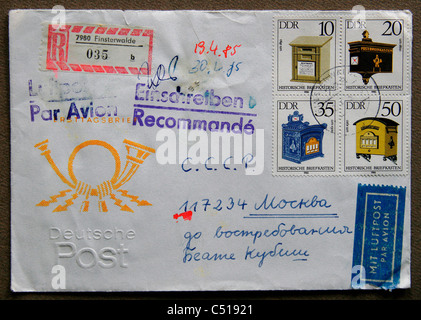 An old envelope of the GDR with stamps showing antiques postboxes and a printed post-horn on the left side. Stock Photo