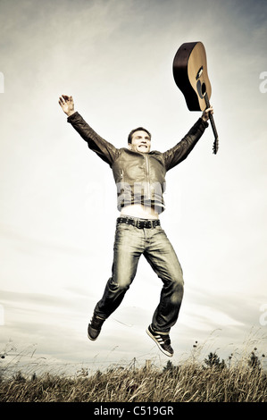 Man jumping with a guitar in his hand Stock Photo