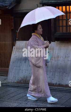 A Japanese Geisha (Geiko) walking along traditional restaurants in the historical Gion district, Kyoto, Japan JP Stock Photo