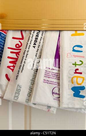 Charity bags (clothes collection fundraiser) posted through door letterbox collecting charitable donations (variety close-up) - Yorkshire, England, UK Stock Photo