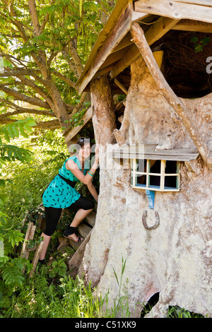 Young woman entering beautiful traditional tree or Wendy house built by Clifford Matthews for his grandchildren. JMH5137 Stock Photo