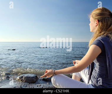 Woman meditating on the beach Stock Photo