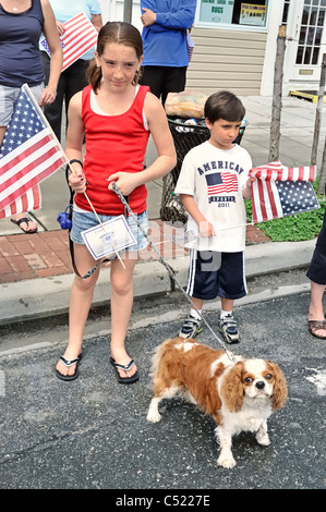 Patriotic freckled girl with spaniel dog, and young boy, watching Memorial Day Parade, Merrick, New York, USA, on May 30, 2011 Stock Photo