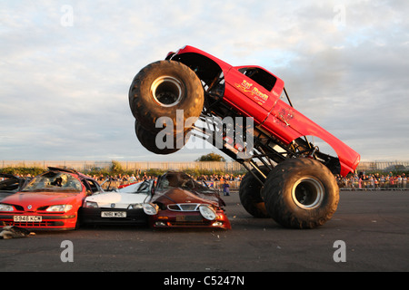 monster truck jumping over crushed cars in a race Stock Photo - Alamy