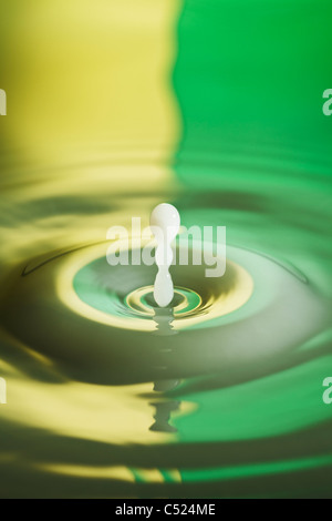 High speed flash photo of milk splashing into water with a reflected yellow and green background Stock Photo