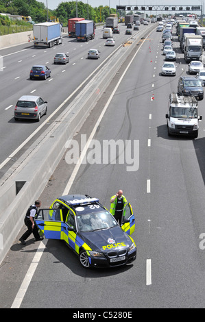 Essex police at  M25 motorway car crash accident under bridge parking in lane 4 with skid marks beyond into concrete crash barrier traffic jam UK Stock Photo