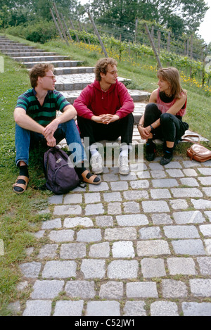 Three German students talk on stone staircase. Stock Photo