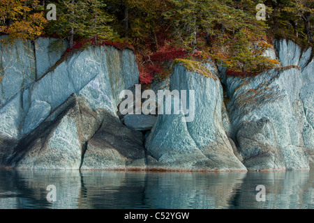 Fall colors line the cliffs along the shoreline of Tracy Arm-Fords Terror Wilderness, Alaska Stock Photo