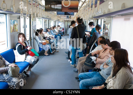 Suburban commuter train with passengers in the middle of the day. Osaka city, Japan. Stock Photo