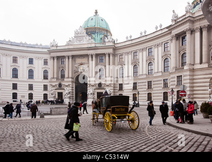 A horse driven carriage crosses in front of the Hofburg Palace in Michaeler Platz. Vienna, Austria. Stock Photo