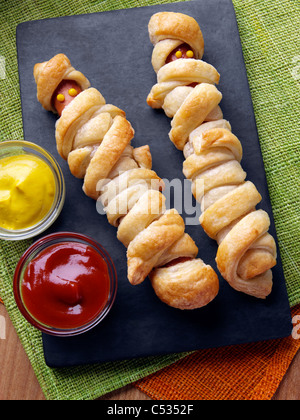 Wrapped frankfurter sausages with mustard and tomato ketchup Stock Photo