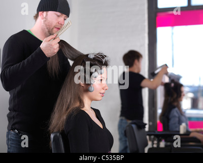 Young woman having her hair done by a hairstylist at a salon Stock Photo