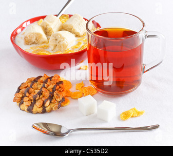 cornflakes with banana in bowl and tea with cookie Stock Photo