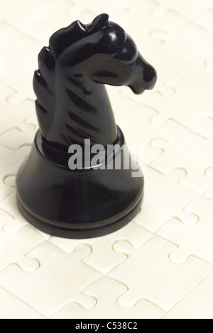 Black knight chess piece on wooden jigsaw puzzle background Stock Photo