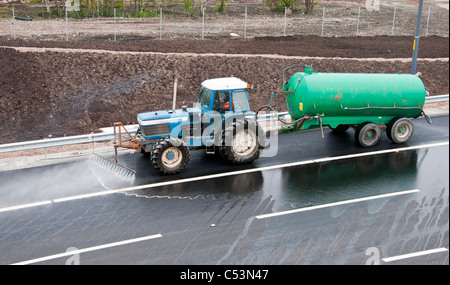 Tractor and water bowser cleaning the M74 extension link prior to the road opening. Stock Photo