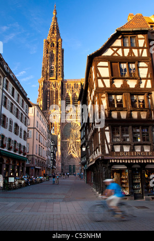 Bicycler rides past the massive Cathedral Notre Dame in Strasbourg, Bas Rhin, Alsace, France Stock Photo