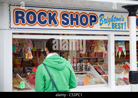 Rock shop - Brighton's best - female at kiosk on Brighton Pier, East Sussex, UK in May Stock Photo