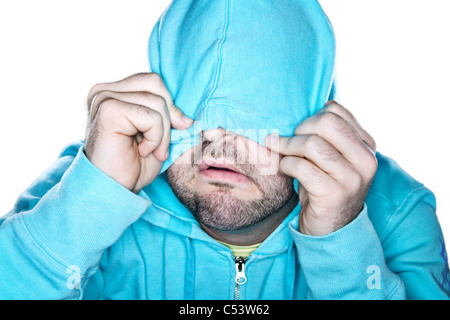 Scruffy man pulling a bright blue hoodie over his face, with a comedic expression. Stock Photo