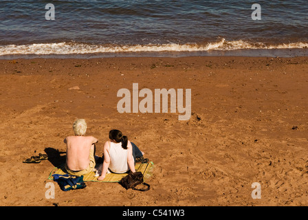 Two sun bathers facing the sea, UK Stock Photo