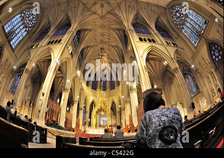 St. Patrick's Cathedral with woman kneeling in pew from behind, domed main altar, Manhattan NYC 2011-06-27 (fisheye lens view) Stock Photo