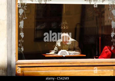 An elderly man sitting an reading in a cafe. Krakow, Poland. Stock Photo