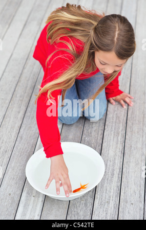 High angle view of a girl touching a fish in a bowl Stock Photo