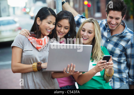 Friends using electronic gadgets outdoors Stock Photo