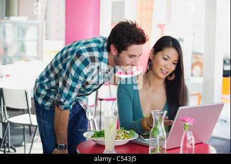 Woman using a laptop with her friend in a restaurant Stock Photo