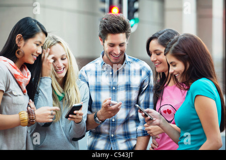 Friends using mobile phones outdoors Stock Photo
