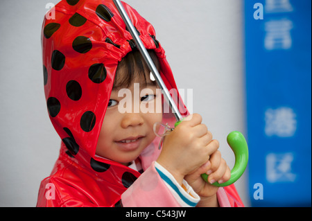 Portrait of a baby boy wearing a raincoat and holding an umbrella, Tokyo, Japan Stock Photo