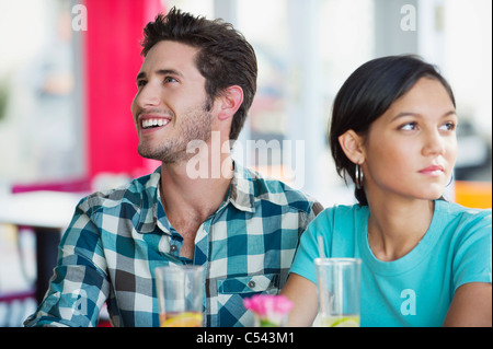 Man smiling with his girlfriend looking sad in a restaurant Stock Photo