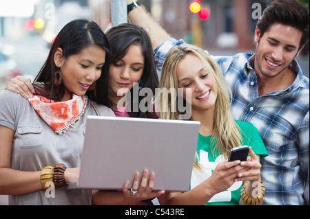 Friends using electronic gadgets outdoors Stock Photo