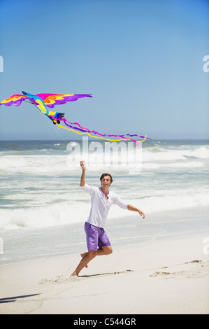 Mid adult man flying kite on the beach Stock Photo