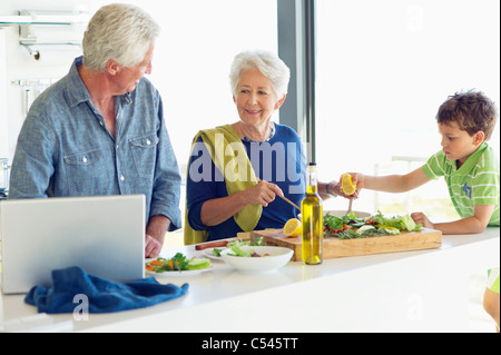 Senior couple with their grandson preparing food in a kitchen Stock Photo