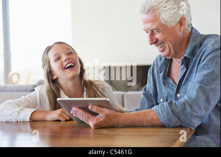 Girl laughing while her grandfather using a digital tablet Stock Photo