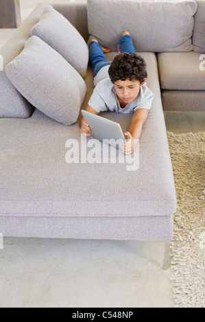 Boy lying on a couch and using a digital tablet Stock Photo