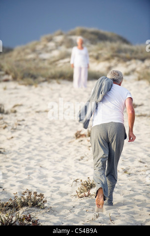 Rear view of a senior man running towards a woman standing in the background Stock Photo