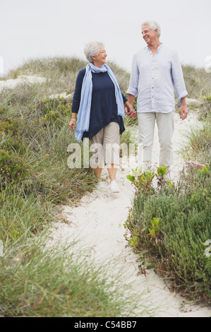 Senior couple walking on the beach with holding hands of each other Stock Photo