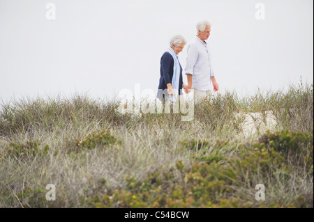 Senior couple walking on the beach with holding hands of each other Stock Photo