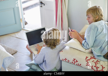 Children using electronic gadgets at home Stock Photo