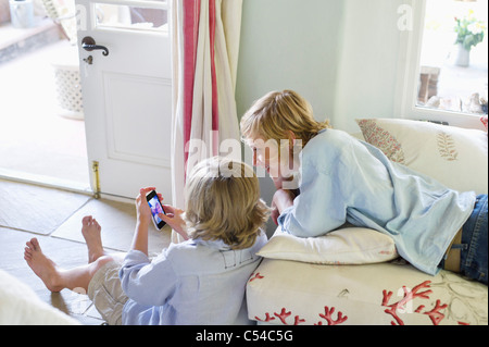 Children using mobile phone at house Stock Photo