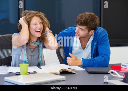 University student consoling his friend in a classroom Stock Photo