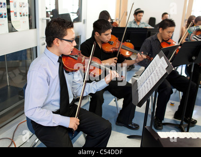 Students play stringed instruments, teacher conducts in orchestra class at Mission Early College High School in El Paso Texas Stock Photo