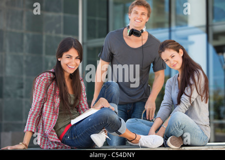 Smiling young students sitting in campus Stock Photo