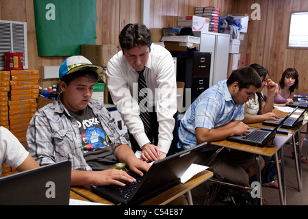 Male teacher helps teen Hispanic student using laptop in classroom at Mission Early College High School in El Paso, Texas Stock Photo