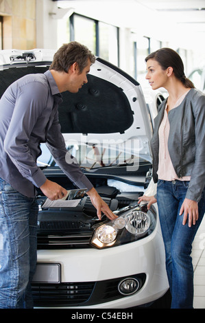 Couple looking at car engine in showroom Stock Photo